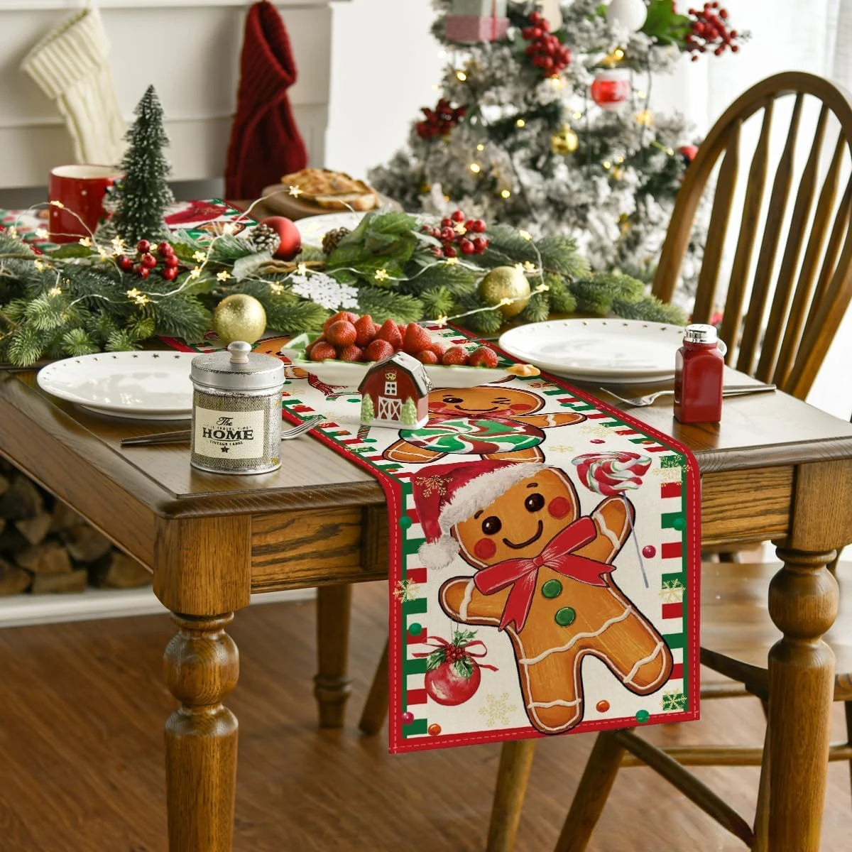 La table décorée présente un arbre de Noël, des guirlandes de houx, des plats de fruits rouges et des objets décoratifs de Noël, offrant une ambiance chaleureuse et festive.