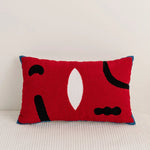 Coussin décoratif en rouge aux formes abstraites aux tons noir et blanc.