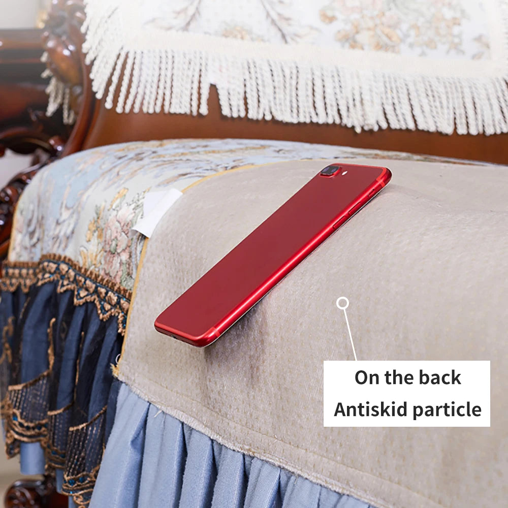 Un téléphone portable rouge se trouve sur un lit décoré de motifs et de franges.