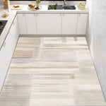 Une cuisine moderne avec des armoires blanches, un comptoir en marbre et un tapis au sol avec des motifs géométriques en nuances de gris et beige.