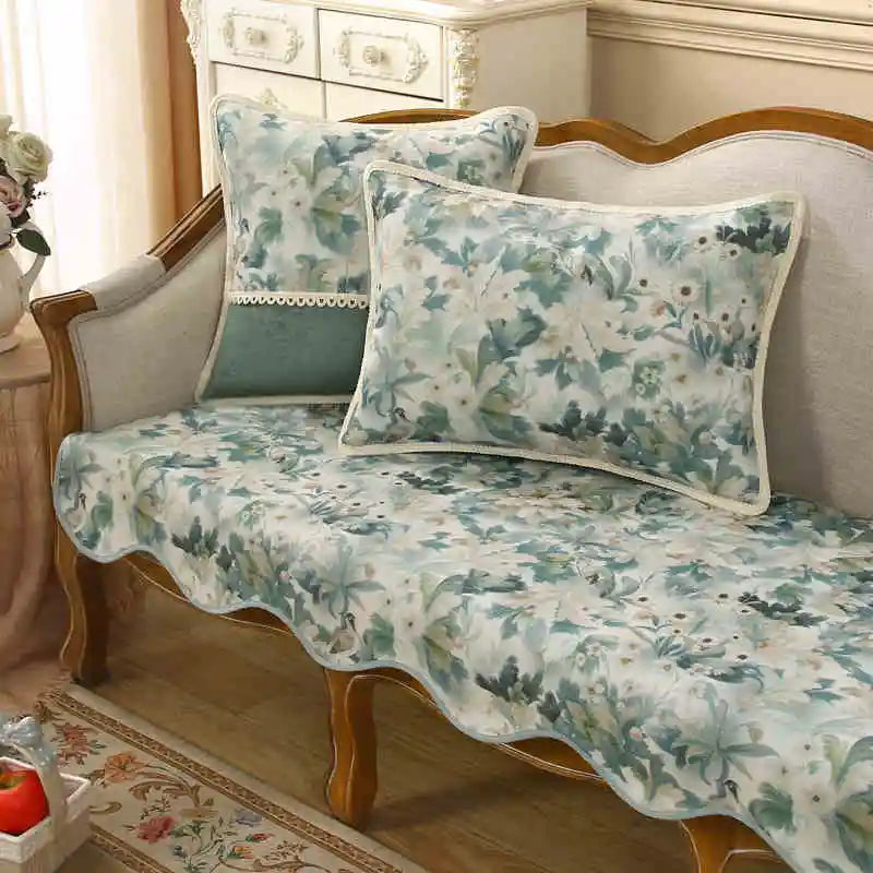 Coussin décoratif avec motif floral en tons bleus et gris, posé sur un canapé en bois à l'ancienne dans un intérieur vintage.