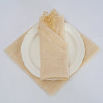 Une serviette de table beige enroulée de manière élégante sur une assiette blanche avec un napperon beige.