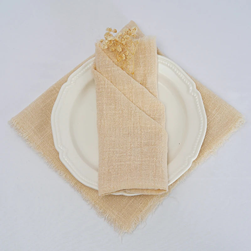 Une serviette de table beige enroulée de manière élégante sur une assiette blanche avec un napperon beige.
