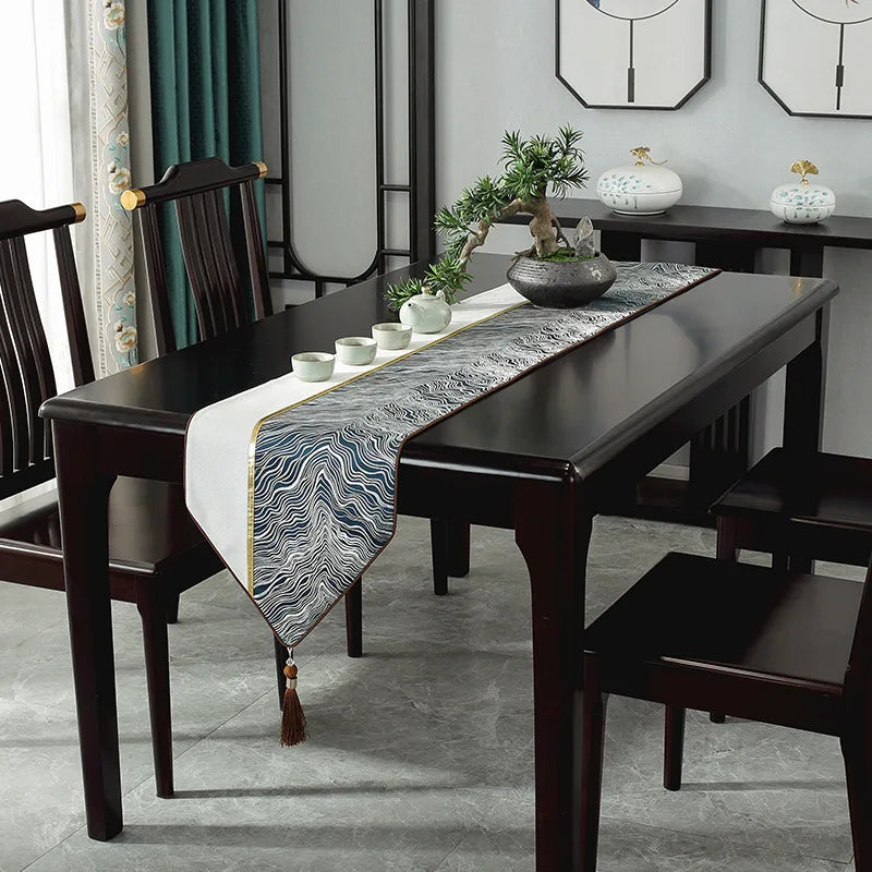 Une table à manger élégante et moderne avec un chemin de table en motif vague et des décorations végétales.