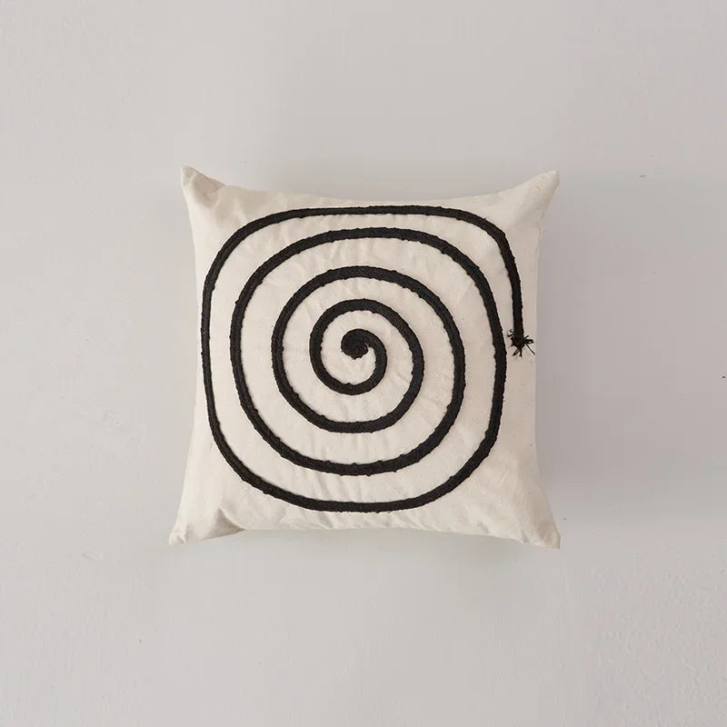 Coussin décoratif avec motif spirale noir et blanc, créant un effet hypnotique et graphique.