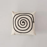 Coussin décoratif avec motif spirale noir et blanc, créant un effet hypnotique et graphique.