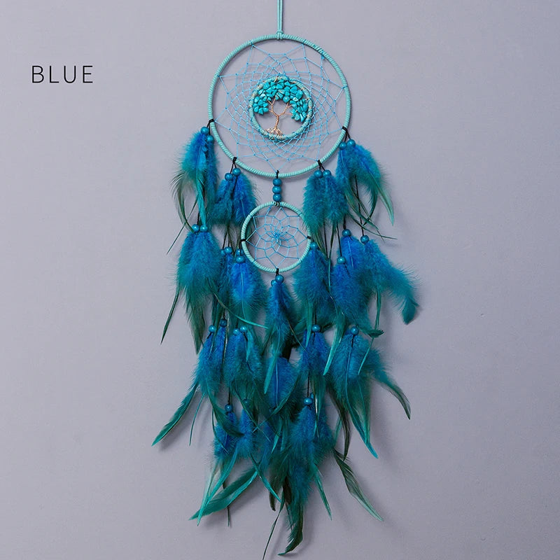 Un attrape-rêves suspendu, constitué de plusieurs cerceaux et de plumes en nuances de bleu et de vert, évoquant une nature apaisante et sereine.