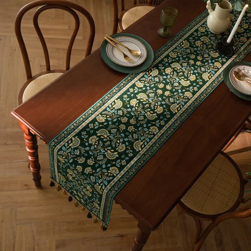Une nappe en coton imprimée de riches motifs floraux dorés rehausse l'élégance de cette table en bois.