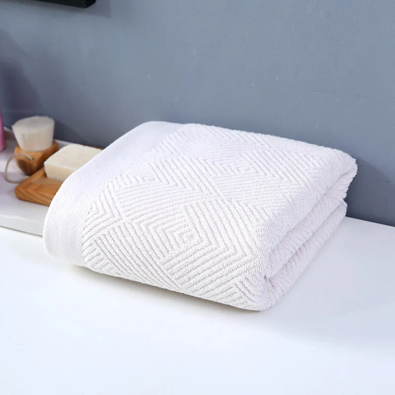 Cette image montre une serviette de bain blanche avec un motif de rayures. L'image est prise dans un environnement de salle de bain avec d'autres accessoires de toilette à proximité.