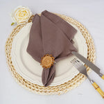 Une belle configuration de table élégante avec une serviette en tissu marron et une fleur blanche sur une assiette blanche et un set de table en osier tressé.