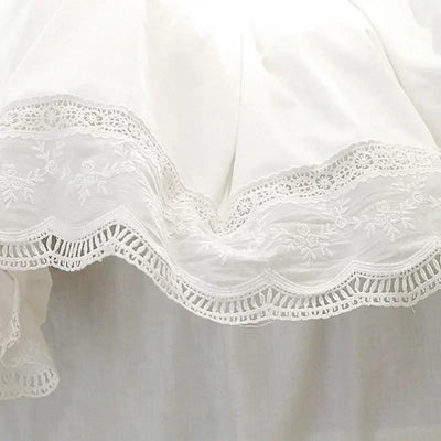 Parure de lit blanche en dentelle brodée avec volants sur un lit