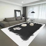 Le salon moderne comporte un canapé gris, un tapis noir et blanc, ainsi que des objets décoratifs blancs et des cadres muraux, créant une atmosphère élégante et épurée.