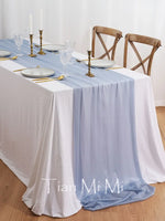 Une table élégante avec une nappe blanche, des chandelles dorées, des verres et des couverts, prête pour un repas spécial.