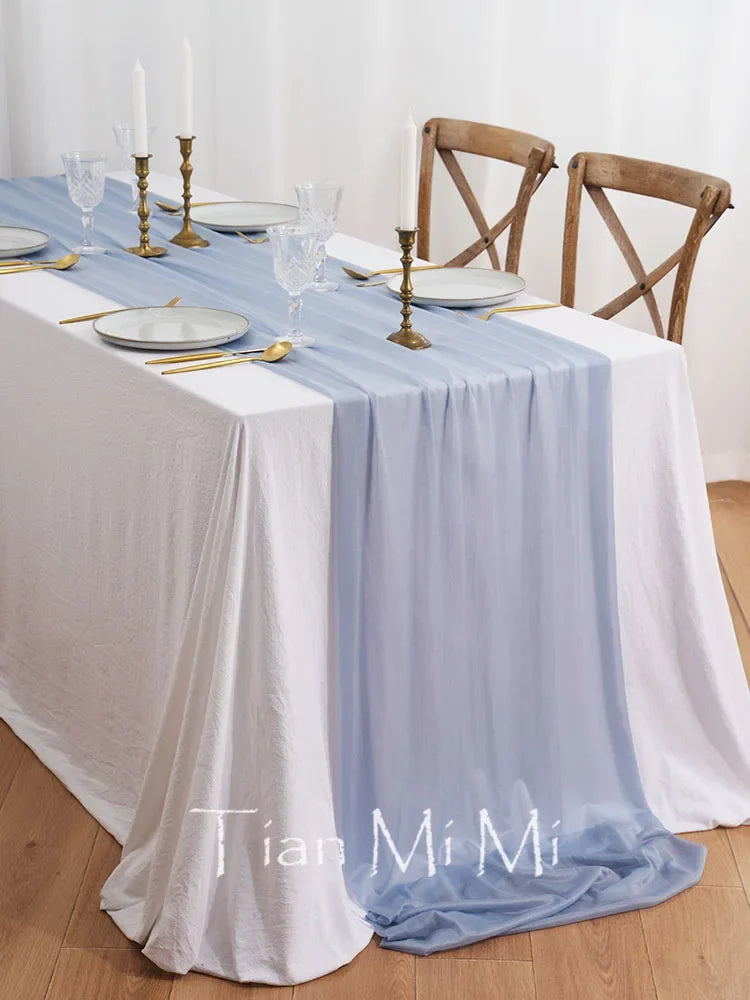 Une table élégante avec une nappe blanche, des chandelles dorées, des verres et des couverts, prête pour un repas spécial.