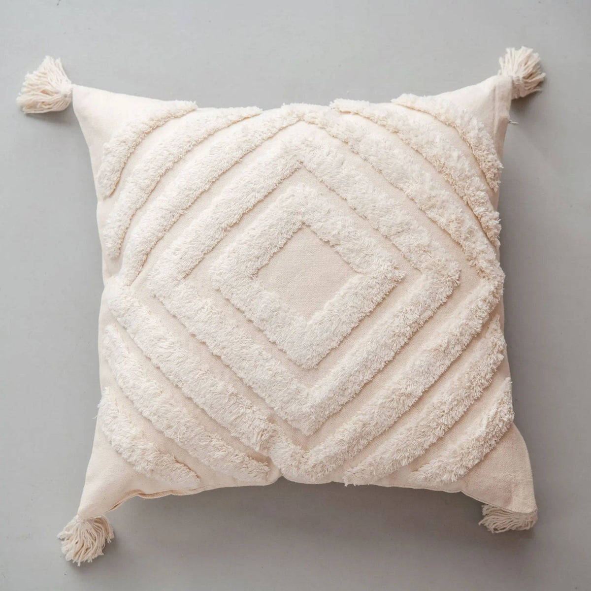 Coussin moelleux beige avec motif géométrique décoratif en relief, créant une texture douce et chaleureuse.