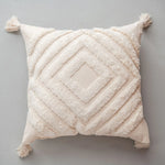 Coussin moelleux beige avec motif géométrique décoratif en relief, créant une texture douce et chaleureuse.