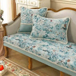 Un canapé vintage aux teintes pastel orné de motifs floraux délicats, assorti de coussins assortis, crée une ambiance élégante et romantique dans cette pièce meublée avec soin.