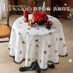 Un joli nappe de table avec des motifs de sapins de Noël festifs sur un fond blanc, créant une ambiance chaleureuse et hivernale pour un repas de fête.