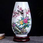 Superbe vase en porcelaine blanc décoré de motifs floraux colorés et d'un oiseau perché sur une branche.