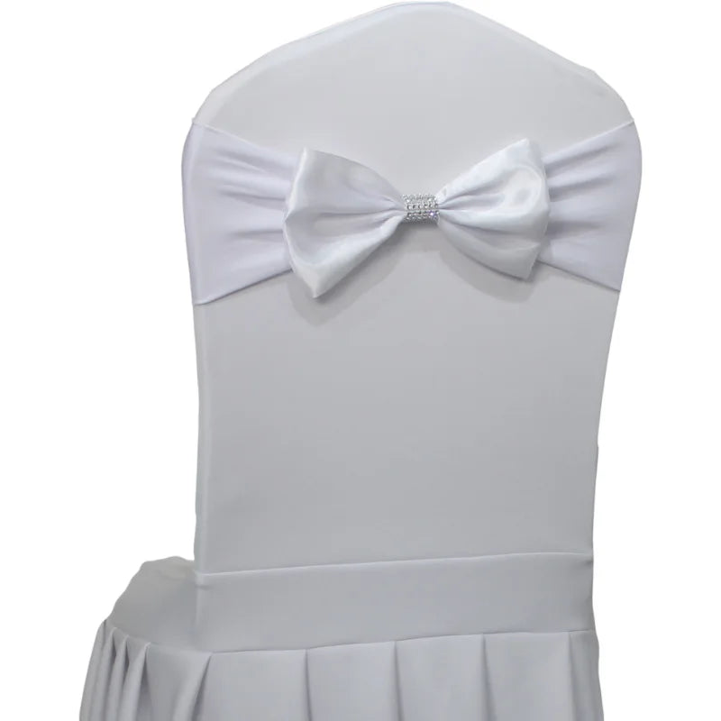 Cette image montre une chaise recouverte de blanc, avec un nœud papillon orné de cristaux au centre du dossier.