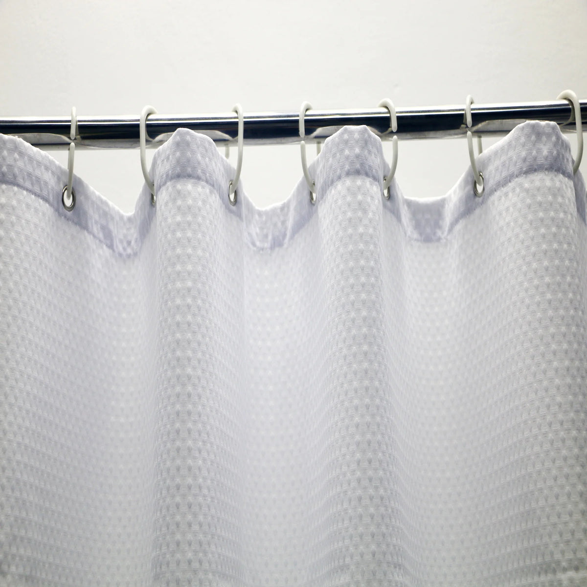 Rideau de douche en maille blanche, ajoutant une touche moderne et élégante à une salle de bain équipée de fixtures de plomberie. Idéal pour compléter n'importe quel décor de salle de bain avec son design unique.