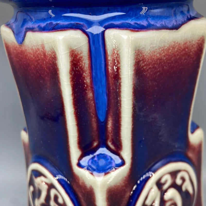 Une goutte de liquide bleue brillante s'écoule sur deux bandes de couleur rouge et blanche, créant une composition graphique intrigante et esthétique.