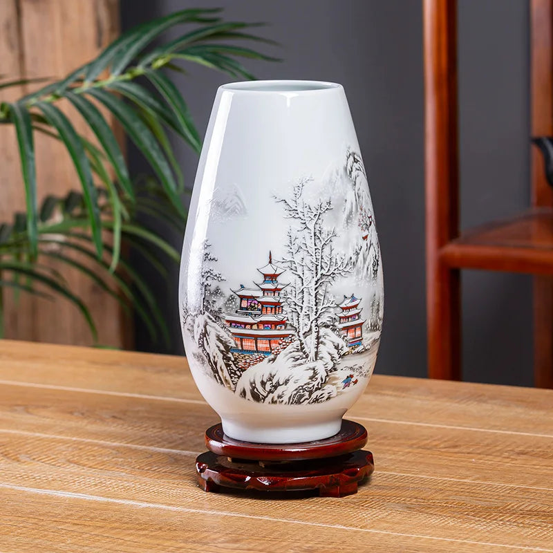 Vase décoratif en porcelaine peint à la main avec un motif de paysage japonais enneigé, composé de pagodes et d'arbres, posé sur un support en bois.