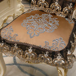 Un coussin décoratif de style baroque avec des motifs floraux et des ornements dorés, offrant une touche d'élégance et de luxe dans un intérieur.