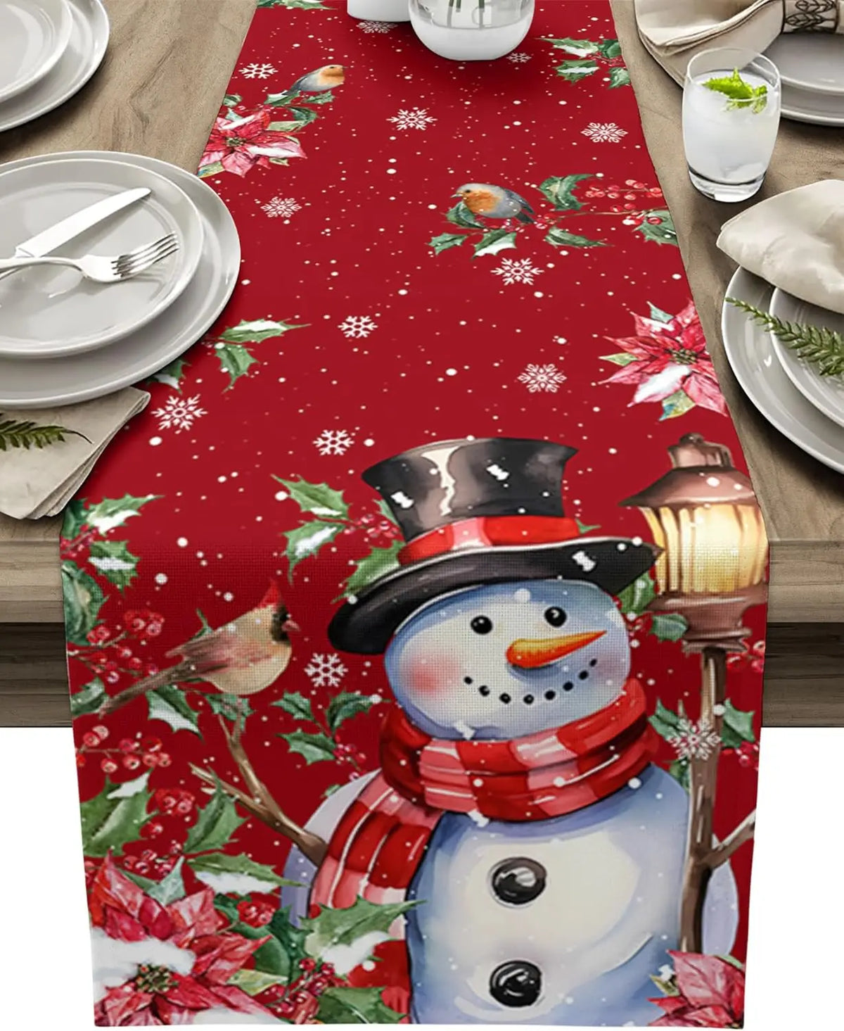 Un chemin de table en tissu rouge orné de motifs de flocons de neige et de personnages de Noël, dont un bonhomme de neige souriant, créant une ambiance festive et chaleureuse pour une table de fête.