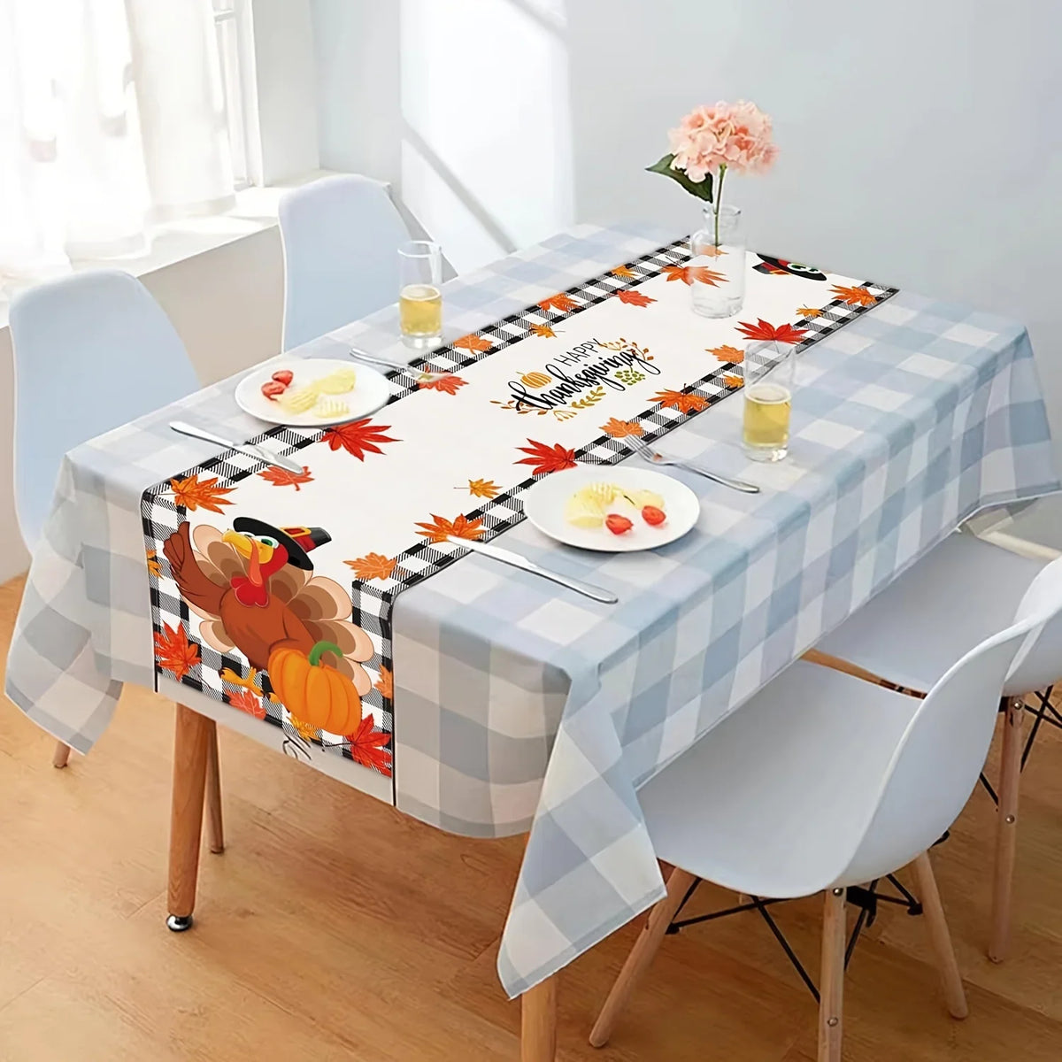 Une table d'automne avec une nappe à carreaux, des feuilles rouges, une belle fleur rose et une décoration de citrouille, créant une ambiance chaleureuse et accueillante pour une célébration automnale.