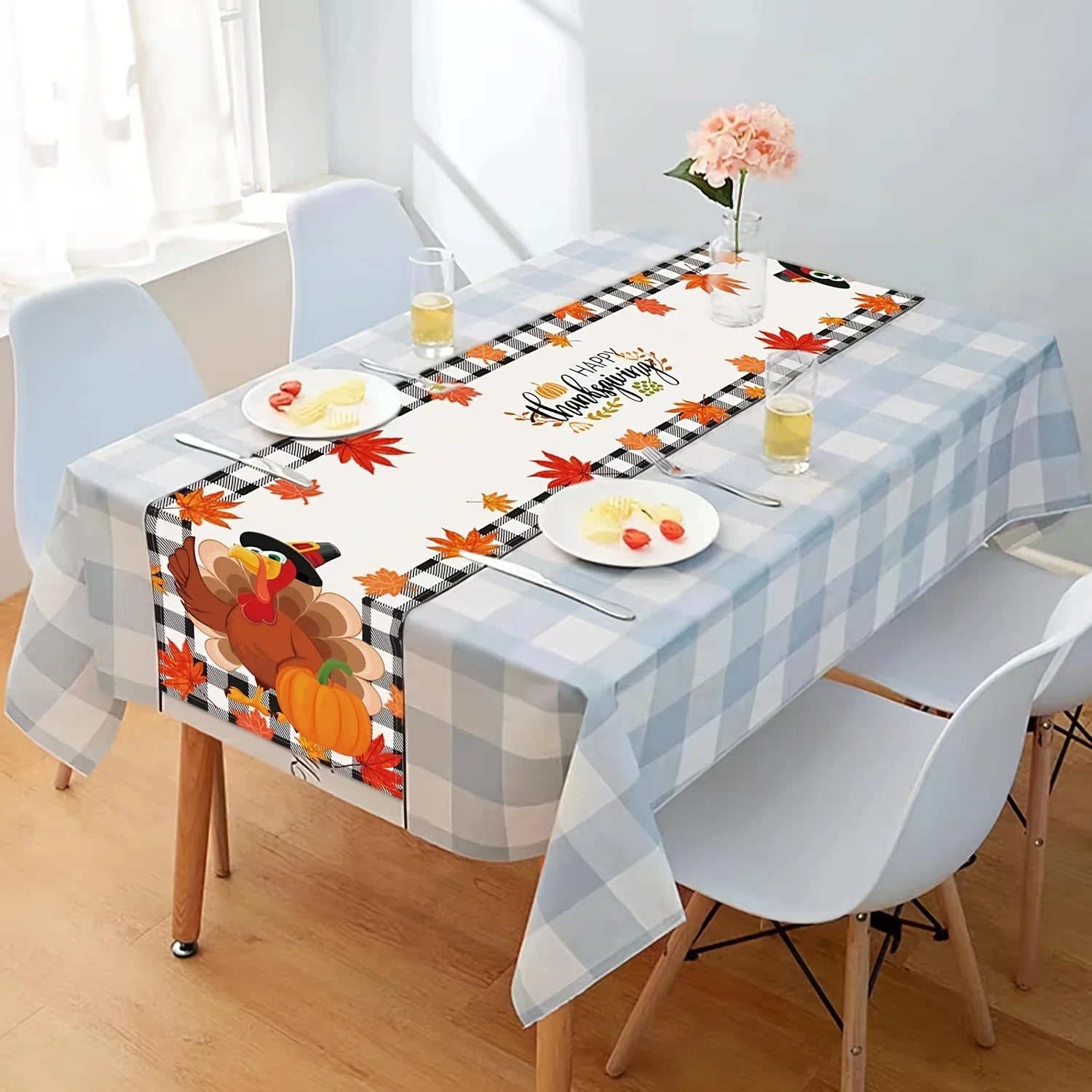 Une table d'automne avec une nappe à carreaux, des feuilles rouges, une belle fleur rose et une décoration de citrouille, créant une ambiance chaleureuse et accueillante pour une célébration automnale.