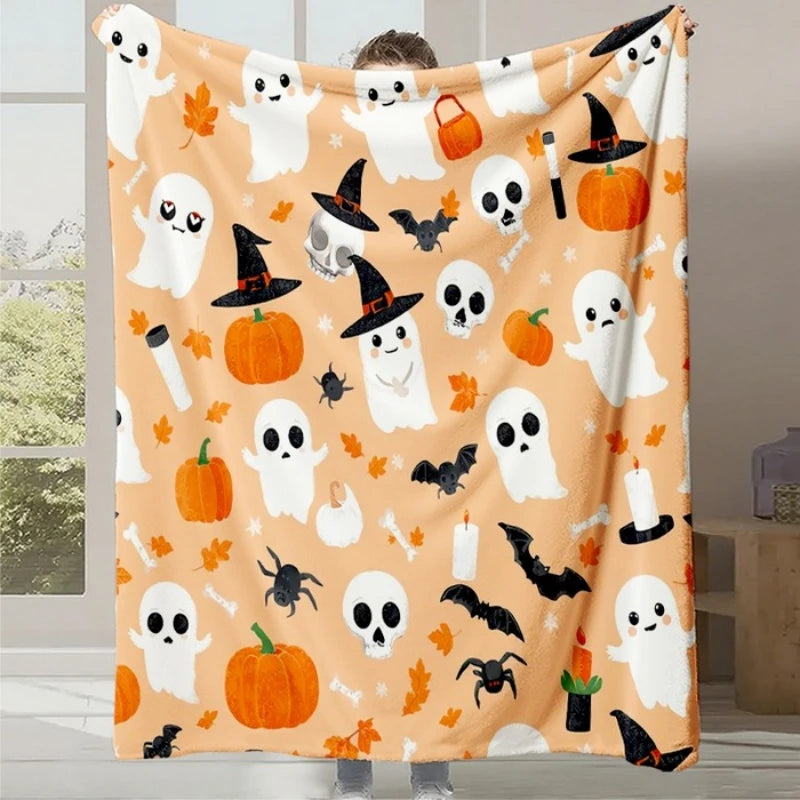 Une couverture à motifs d'halloween, avec des fantômes, des citrouilles, des chauves-souris et des feuilles d'automne sur fond orange.