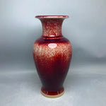 Vase en céramique de couleur rouge avec des motifs texturés, créant un effet de surface vitrifiée.