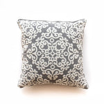 Coussin décoratif gris à motifs damassés blancs.