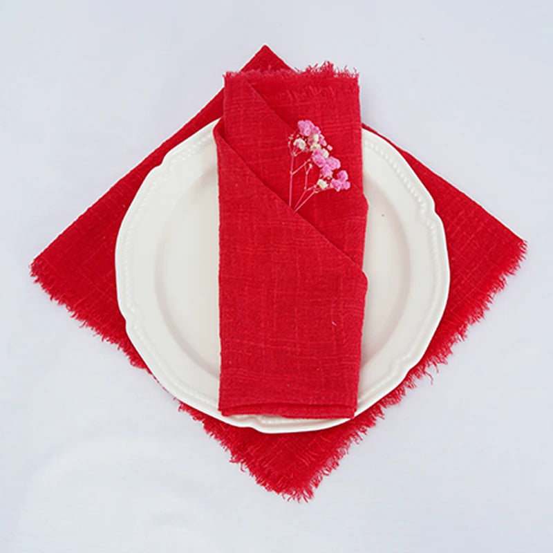 Une serviette de table rouge sur une assiette blanche, avec une décoration florale délicate.
