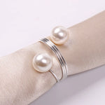 Un élégant bracelet en argent orné de perles blanches posées sur un tissu beige.