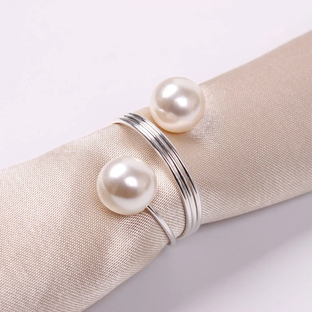 Un élégant bracelet en argent orné de perles blanches posées sur un tissu beige.