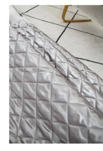 Couverture matelassée gris clair avec design géométrique moderne, vue de près. Idéale pour une décoration intérieure élégante et contemporaine.