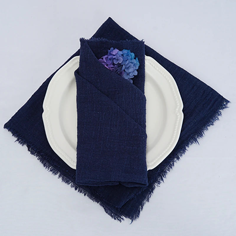 Serviette de table bleue marine ornée d'une fleur bleue et violet sur une assiette blanche, créant une ambiance élégante et raffinée.