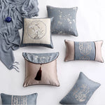 Des coussins décoratifs aux motifs géométriques et floraux dans des tons de gris et beige, accompagnés d'une couverture en velours gris, créent une ambiance élégante et apaisante dans cette composition.