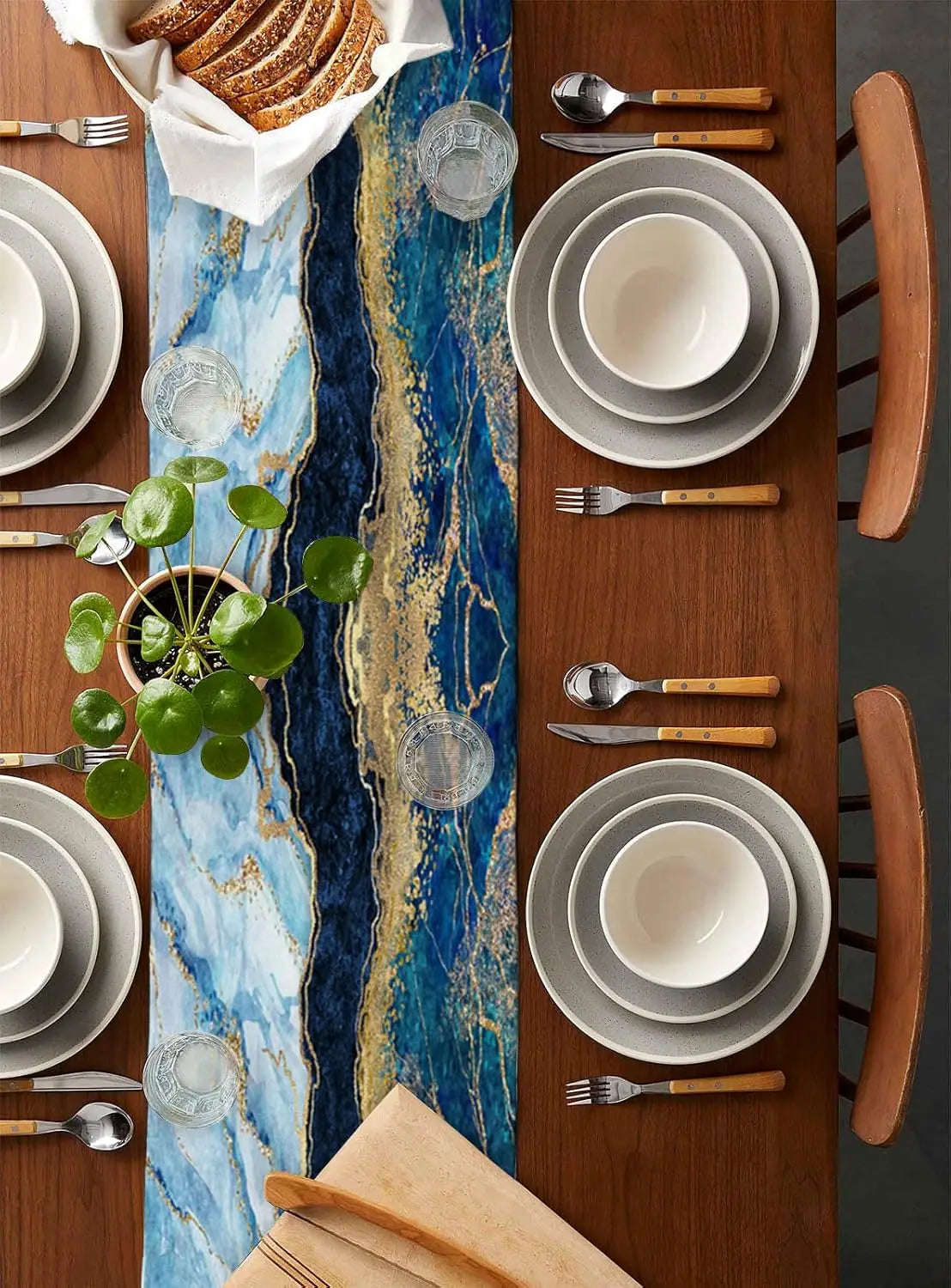 L'image montre une table de cuisine élégante avec des assiettes, des couverts et des accessoires de style rustique, ainsi qu'une plante verte ajoutant une touche de fraîcheur à la composition.
