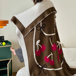 Couverture ou plaid douillet en tissu éponge marron décoré de cerises rouges et de noeuds.