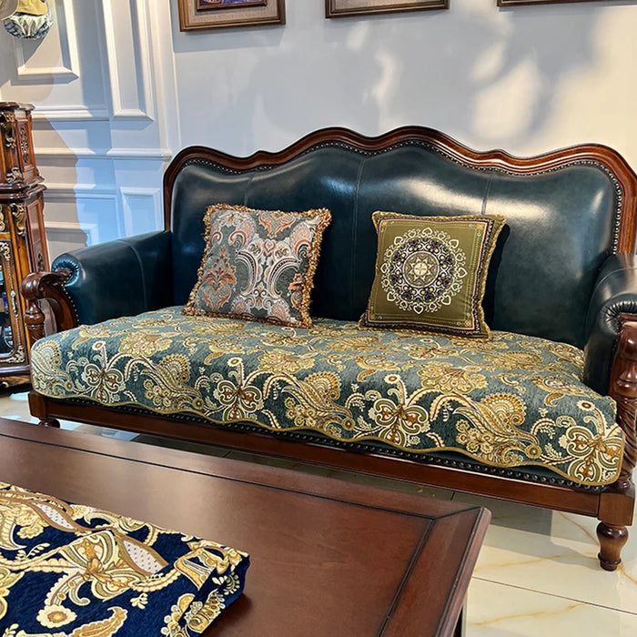 Un canapé vintage avec un dossier en cuir noir et des coussins aux motifs baroques dorés et verts, créant une atmosphère élégante et luxueuse dans cette pièce.