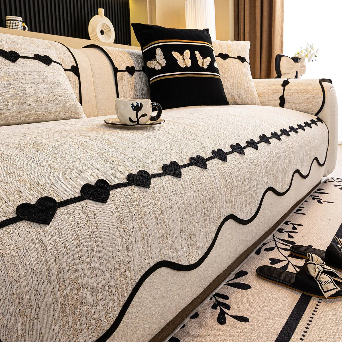 Coussins et couverture décorative avec motifs de fleurs et papillons sur un canapé élégant dans un intérieur moderne.