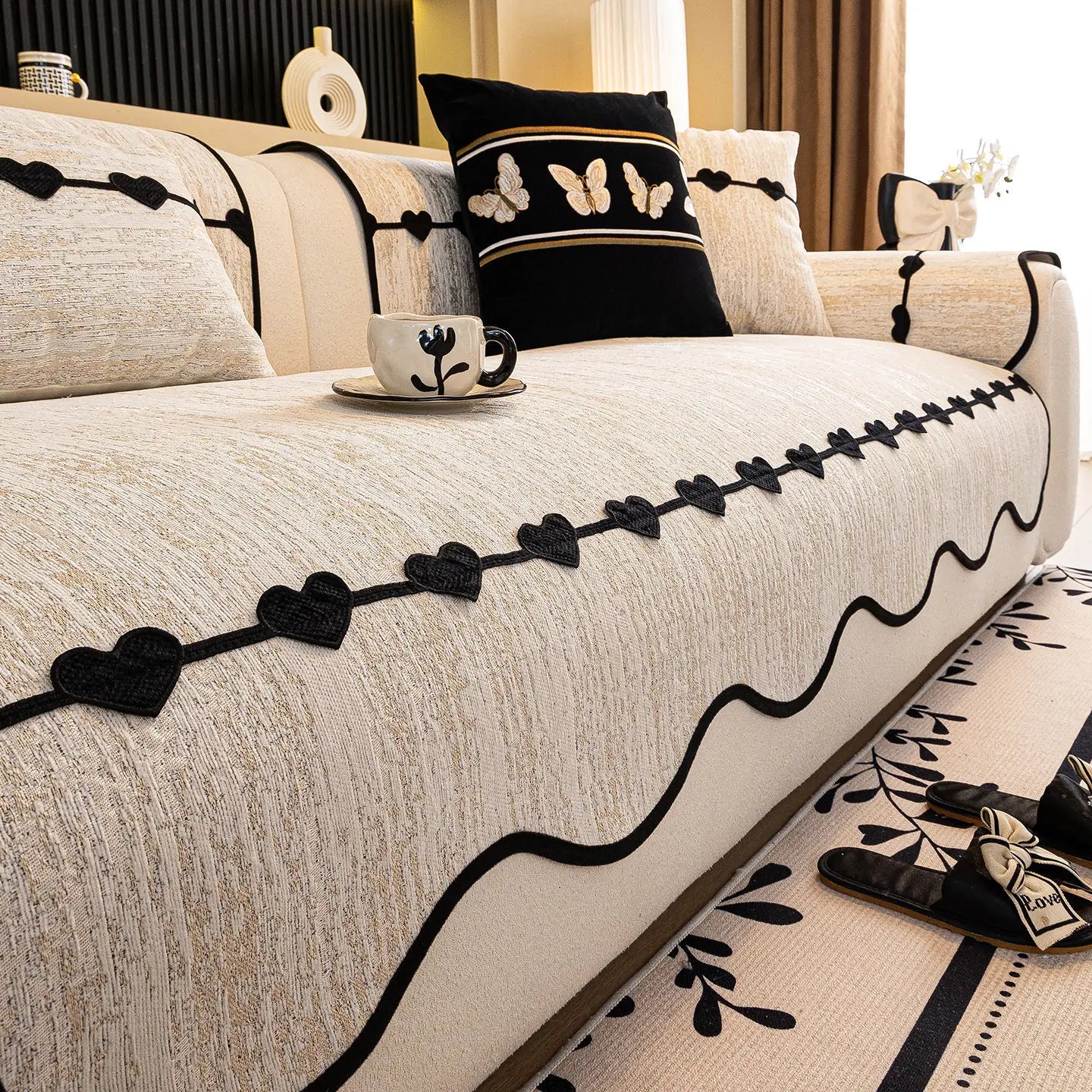 Coussins et couverture décorative avec motifs de fleurs et papillons sur un canapé élégant dans un intérieur moderne.