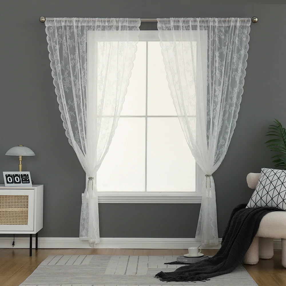 Voilage blanc en dentelle encadrant une grande fenêtre dans un salon cosy aux murs gris.