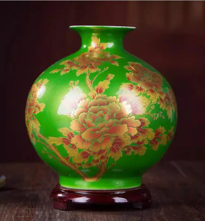 Un vase en céramique de couleur verte décoré de fleurs de pivoines dorées sur un fond sombre.
