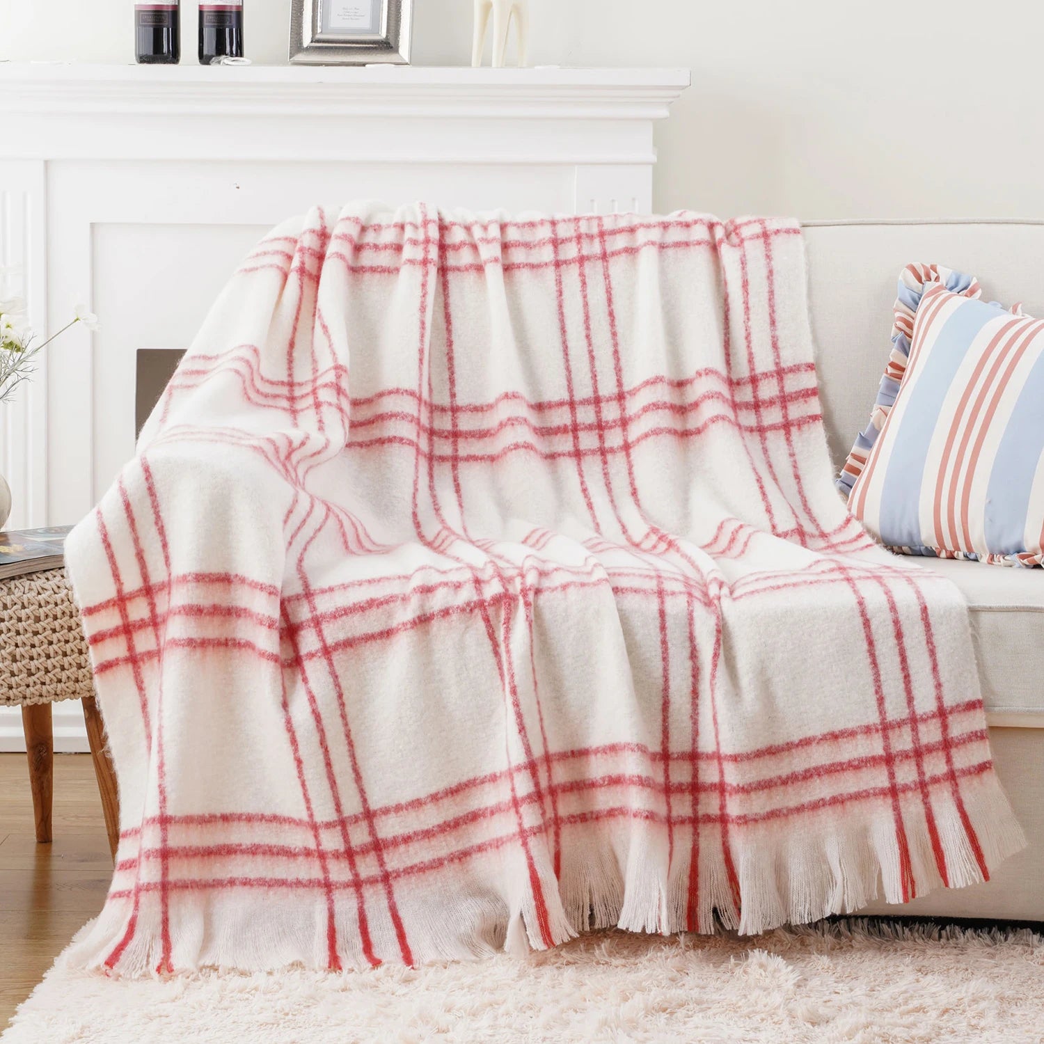 Une douce couverture blanche aux rayures rouges ornée de pompons apporte une touche chaleureuse et accueillante à cette scène d'intérieur cocooning.