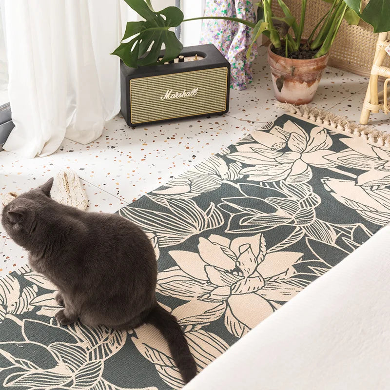 Un chat sombre se repose sur un tapis motif floral devant un amplificateur Marshall dans un intérieur décoré de plantes vertes.