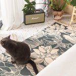Un chat sombre se repose sur un tapis motif floral devant un amplificateur Marshall dans un intérieur décoré de plantes vertes.
